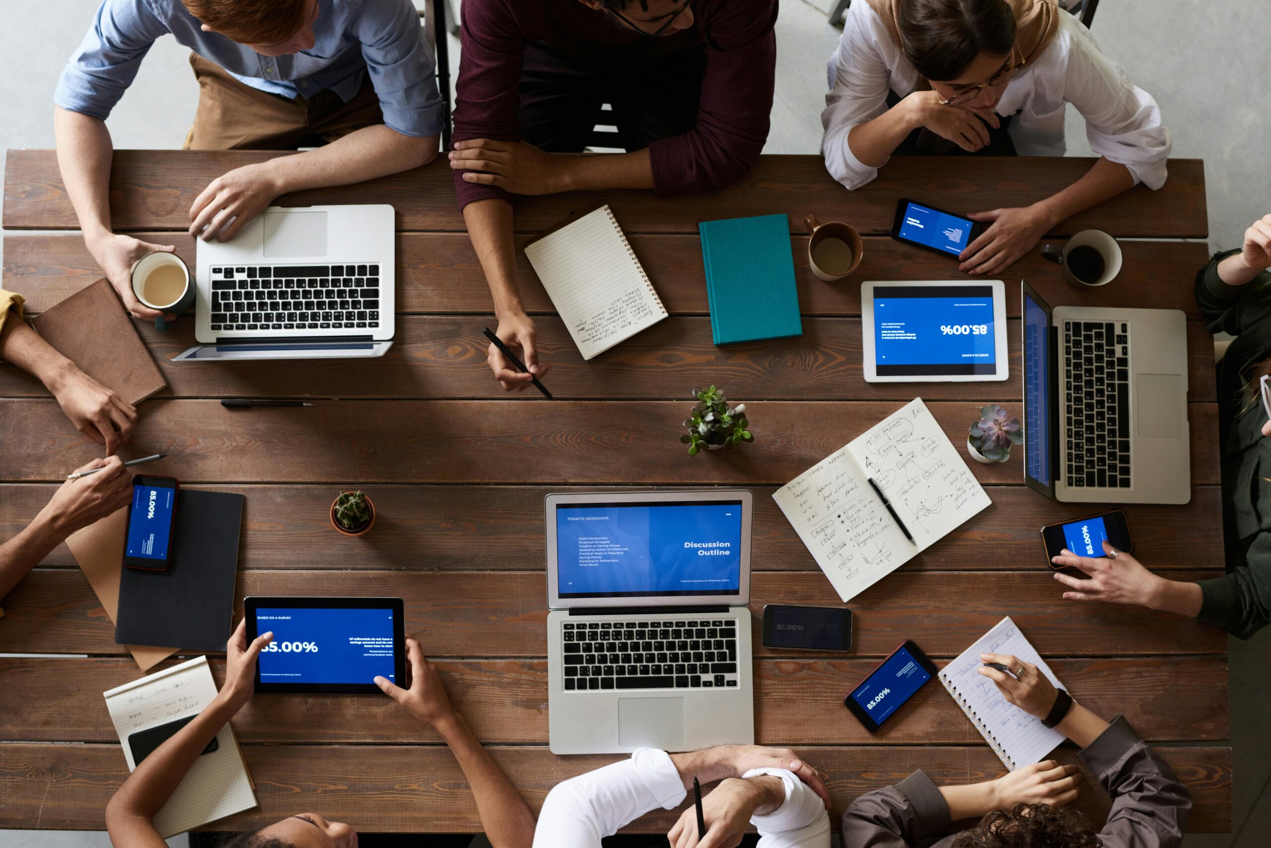 SEFNET Overhead view of a diverse team in a business meeting using laptops and tablets.